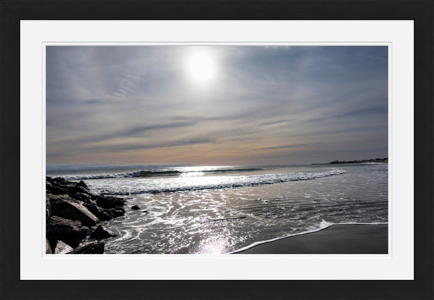 Sunset over a beach with waves and rocks, framed with a white border.